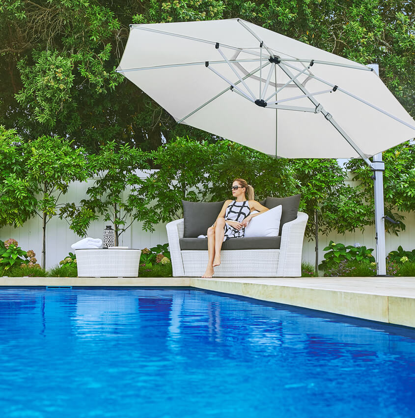 Frankford Cantilever umbrella shading a woman sitting by a pool