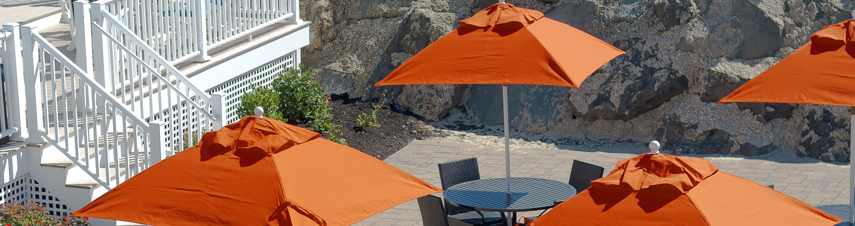 Orange and square Frankford Market Umbrellas set up over tables at a large property