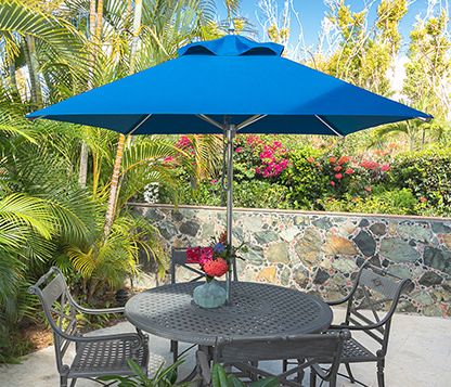A Frankford blue Greenwich Aluminum Square Market Umbrella shades a small table and chairs at a home in St. John, USVI